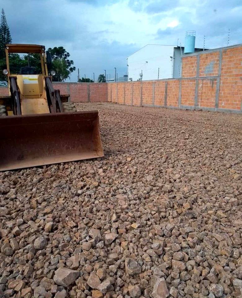 Pá carregadeira espalhando cascalho em obra